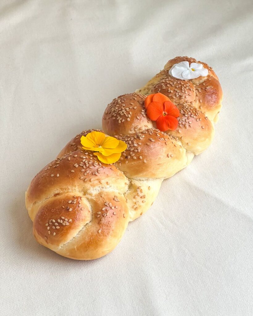 pain traditionnel brioché, tressé à la main, au teint doré, parsemé de graines de sésame, et à la mie briochée ultra moelleuse.